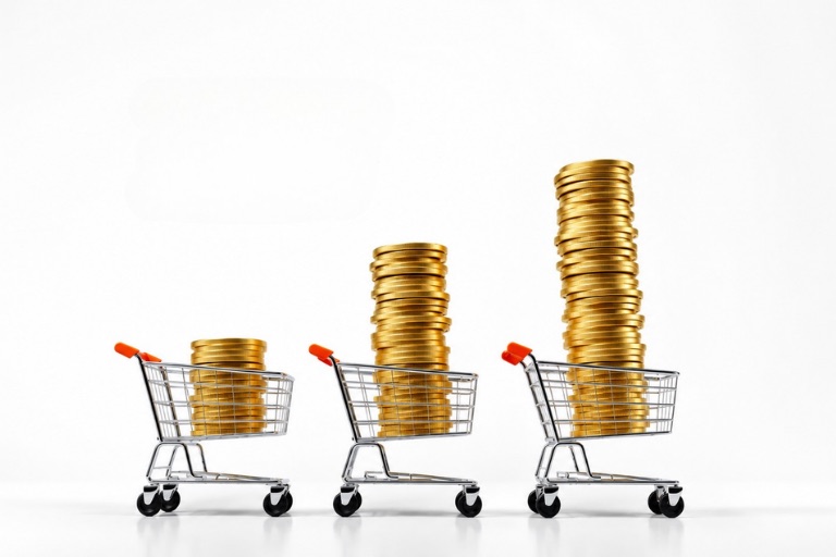 Three shopping carts holding progressively larger stacks of gold coins, showing growth built on ad spend efficiency