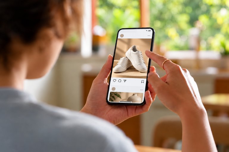 A person scrolling a social feed on a phone past a sponsored post for white sneakers, the same ad creative seen again